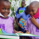 Children in masks read books donated to Books for Africa
